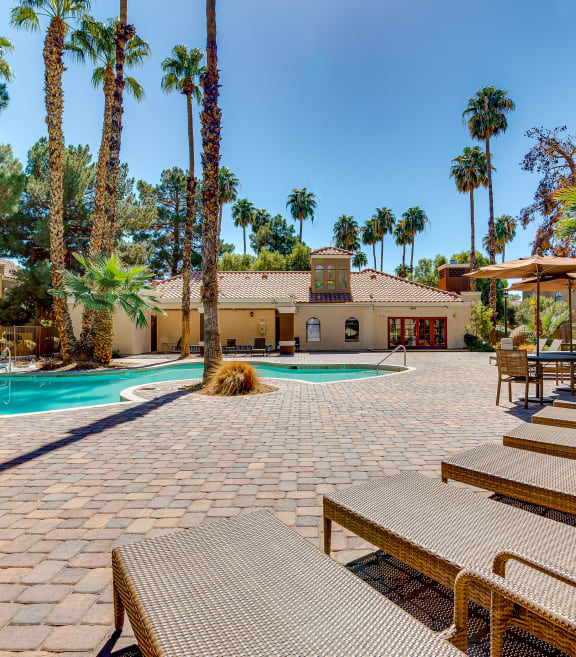 a swimming pool with chairs and a house in the background