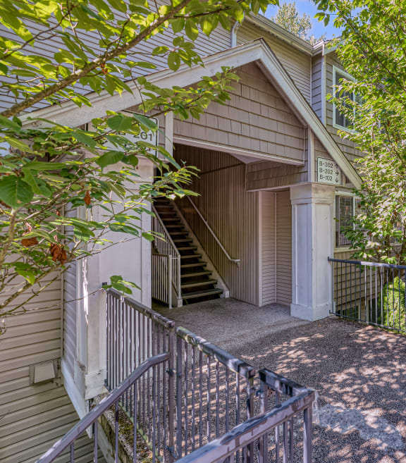 a house with stairs and a sidewalk with trees