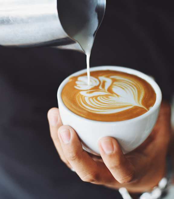 A person is pouring milk into a cup of coffee.