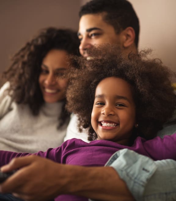 a young girl is sitting on a couch with her parents