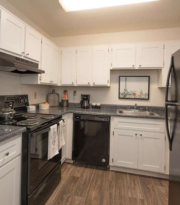River Pointe apartments model unit kitchen with black appliances and white cabinets 