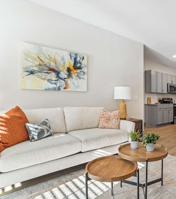 A living room with a white couch and a painting on the wall.