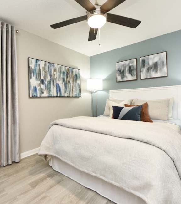 A bedroom with a large bed and a ceiling fan.