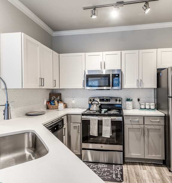A modern kitchen with a stainless steel refrigerator, microwave, and oven.