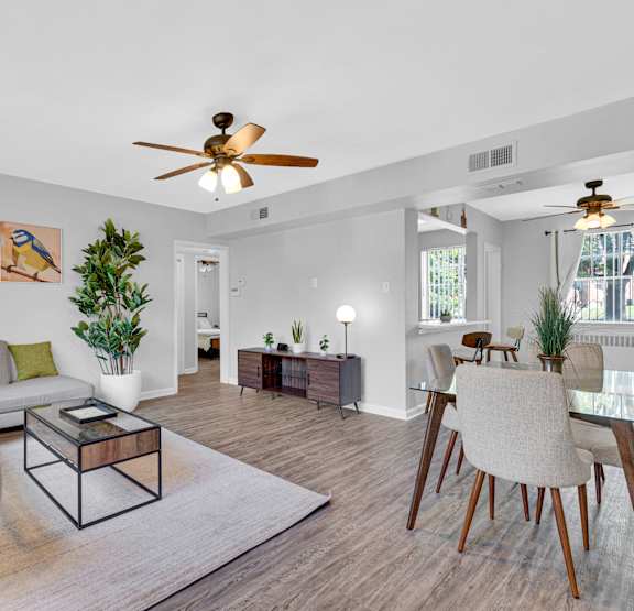 a living room with a ceiling fan and a dining room table with chairs