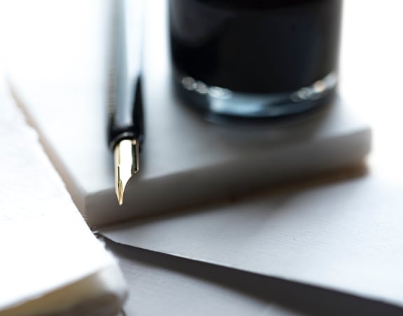 a pen sitting on top of a piece of paper next to a pen