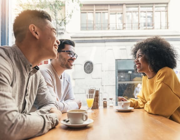 a group of people sitting at a table talking and laughing