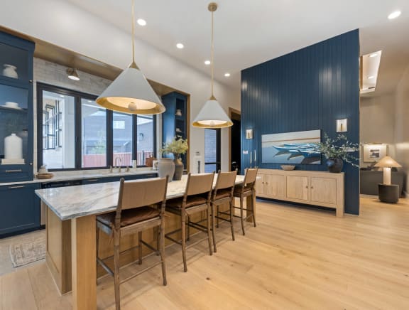 a large kitchen with a long island with chairs and a blue accent wall