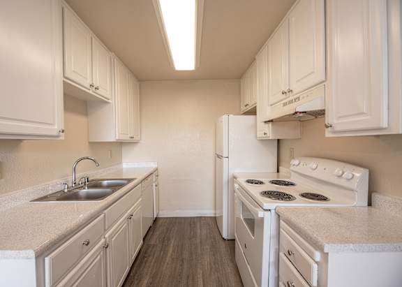 A white kitchen with a sink and stove.