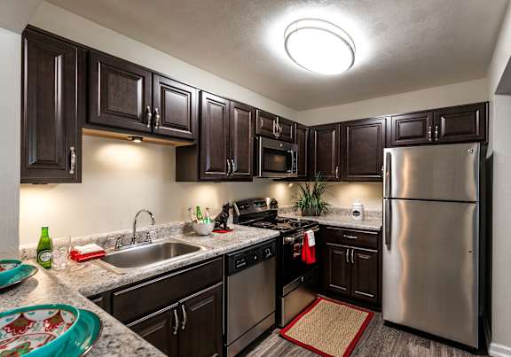 A kitchen with dark brown cabinets and a stainless steel refrigerator.