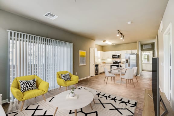 a living room and kitchen with yellow chairs and a table