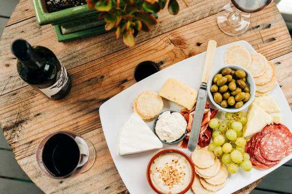 a plate of cheese and grapes on a table with a bottle of wine
