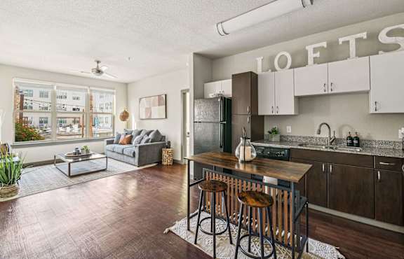 A kitchen with a bar and stools in front of it.