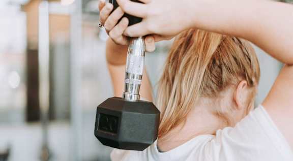 A woman lifting a dumbbell in a gym.