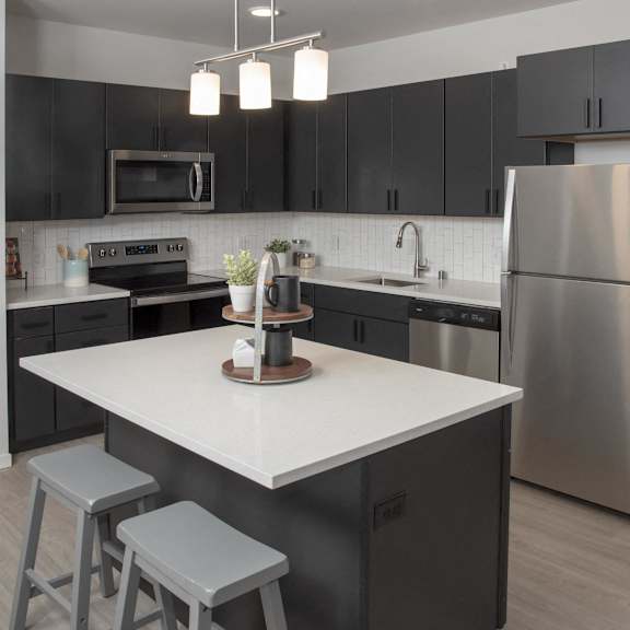 A modern kitchen with a white island and stainless steel appliances.