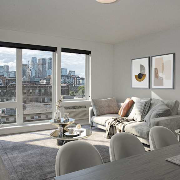 A living room with a grey couch and a table with a vase of flowers on it.
