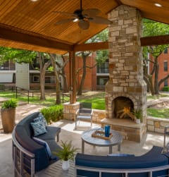 a covered patio with a fireplace and seating