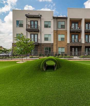 an open field of grass in front of an apartment building