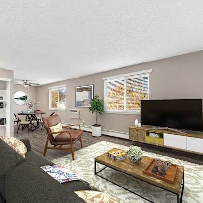 A living room with a grey couch, a wooden chair, a coffee table, and a flat screen TV.