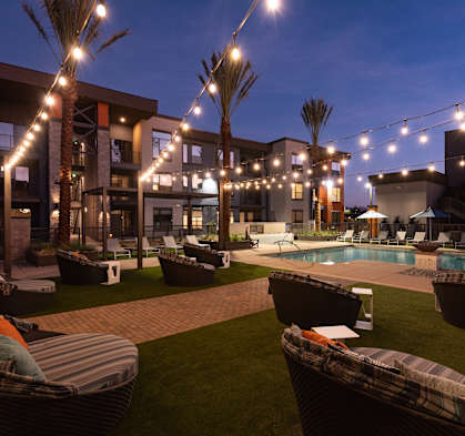 A pool surrounded by lounge chairs and palm trees.