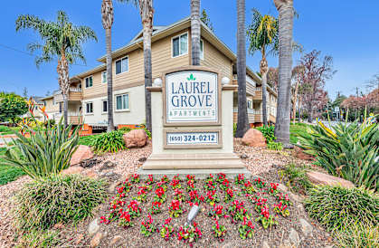 A sign for Laurel Grove Apartments stands in front of a building with a flower bed in the foreground.