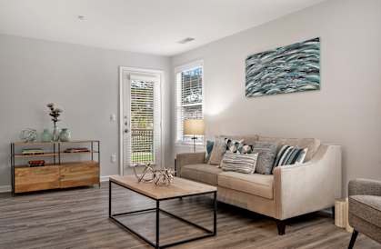 A living room with a couch, a coffee table, and a painting on the wall.