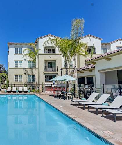 A swimming pool surrounded by lounge chairs and palm trees.