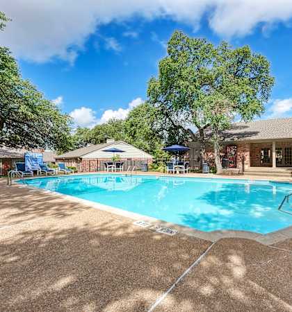 A pool surrounded by trees and a house.