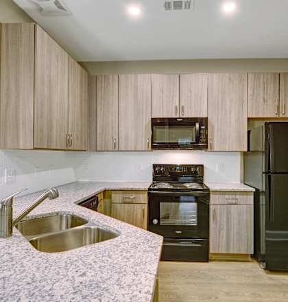 an updated kitchen with granite counter tops and wooden cabinets