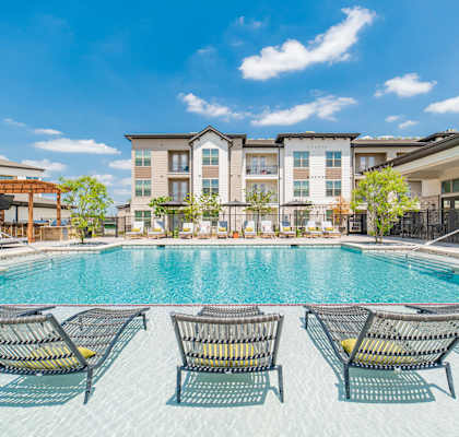 a swimming pool with lounge chairs and buildings in the background