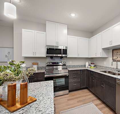 a kitchen with white cabinets and granite counter tops and stainless steel appliances at The Landing at Amber Fields Apartments, Rosemount, 55068