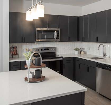 A modern kitchen with a stainless steel refrigerator and black cabinets.