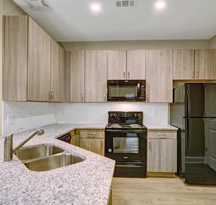 an updated kitchen with granite counter tops and wooden cabinets