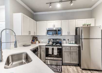 A modern kitchen with a stainless steel refrigerator, microwave, and oven.