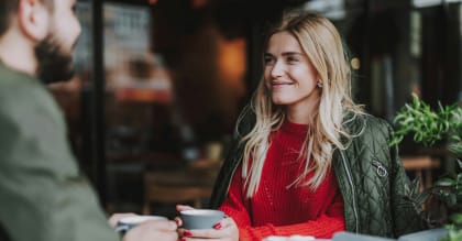 a woman sitting at a table with a cup of coffee