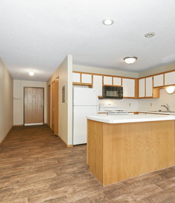 Anoka, MN Dellwood Estates Apartments. a kitchen with white appliances and wooden cabinets