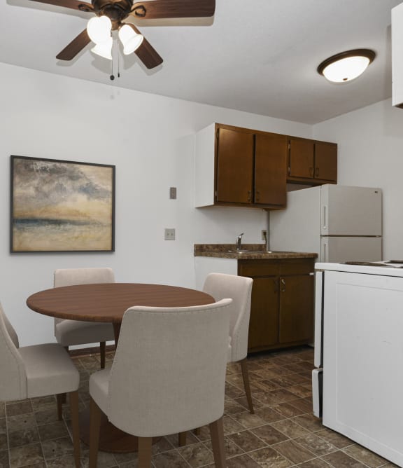 a dining area  in west st paul at Covington apartments with a table and 4 chairs and a kitchen in the background