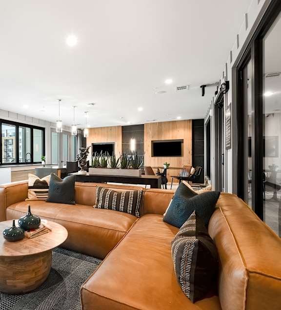 A modern living room with a large brown leather couch and a wooden coffee table.