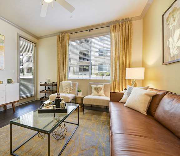 A living room with a brown leather couch and a glass coffee table.