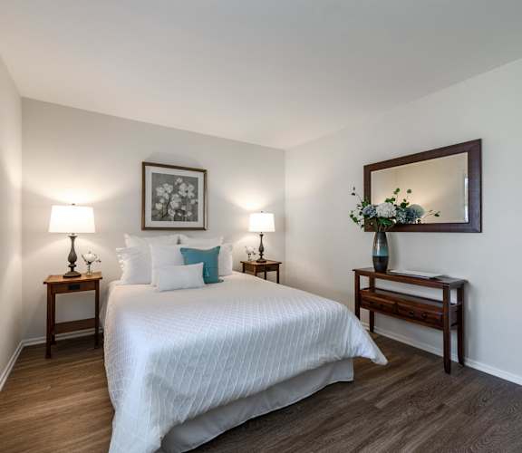 A bedroom with a bed, two nightstands with lamps, and a mirror.