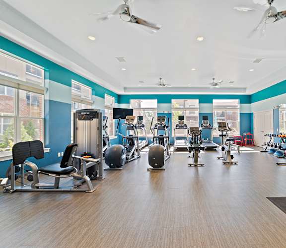 A gym with a variety of equipment including treadmills, weights, and exercise machines.