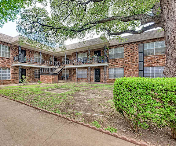 A large tree is in front of a brick building.