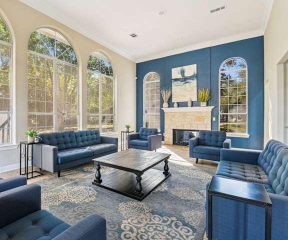 a living room with blue couches and chairs and a fireplace at TalaVera Apartments, Texas, 78232