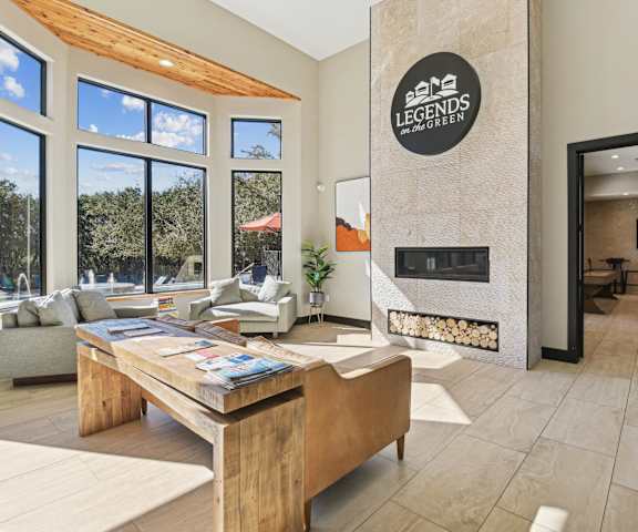 a living room with a fireplace and a wooden table  at Legends on the Green Apartments, San Antonio, 78232
