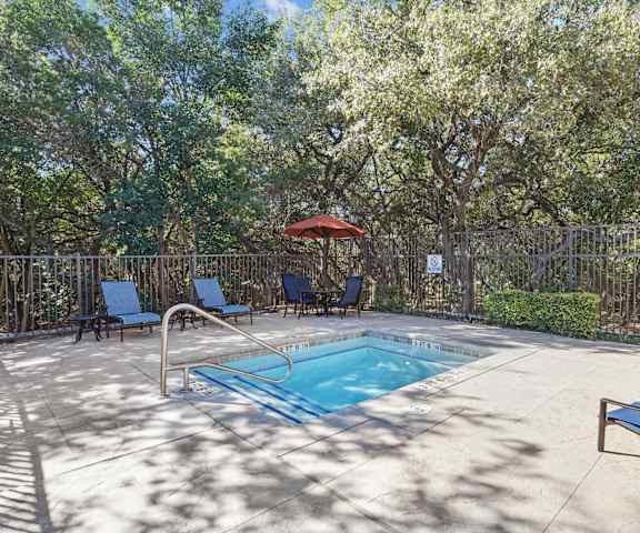 a swimming pool with chairs and an umbrella in a backyard