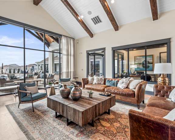 A living room with a brown leather couch and a wooden coffee table. at Ovation at Town Madison, Madison, Alabama