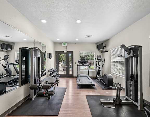 A gym with a variety of equipment including treadmills, weights, and exercise machines.