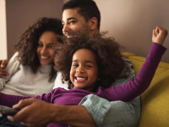 a young girl is sitting on a couch with her parents