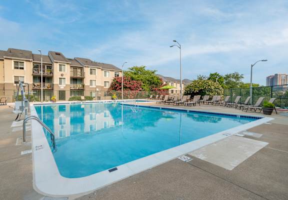 A large outdoor swimming pool with a white edge and a white ramp leading into the water.
