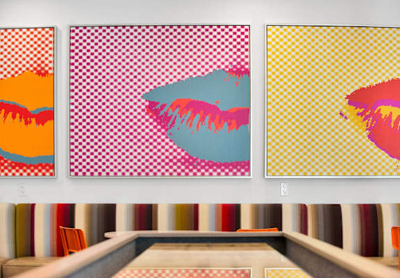 three paintings of lips on a wall in a room